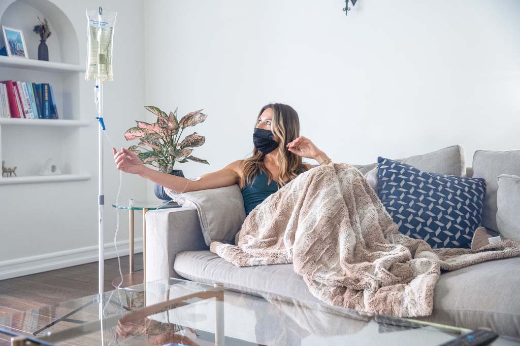 woman getting an IV therapy on her couch